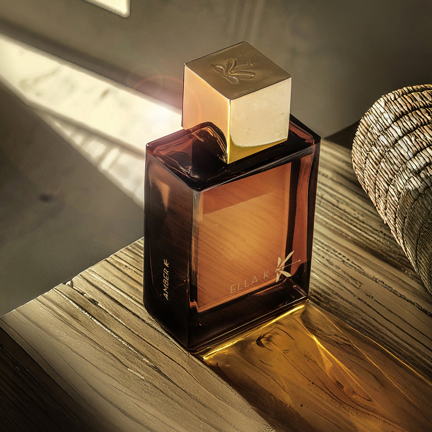 Flacon debout du parfum Amber K d’Ella K avec reflets lumineux sur bois – vue rapprochée