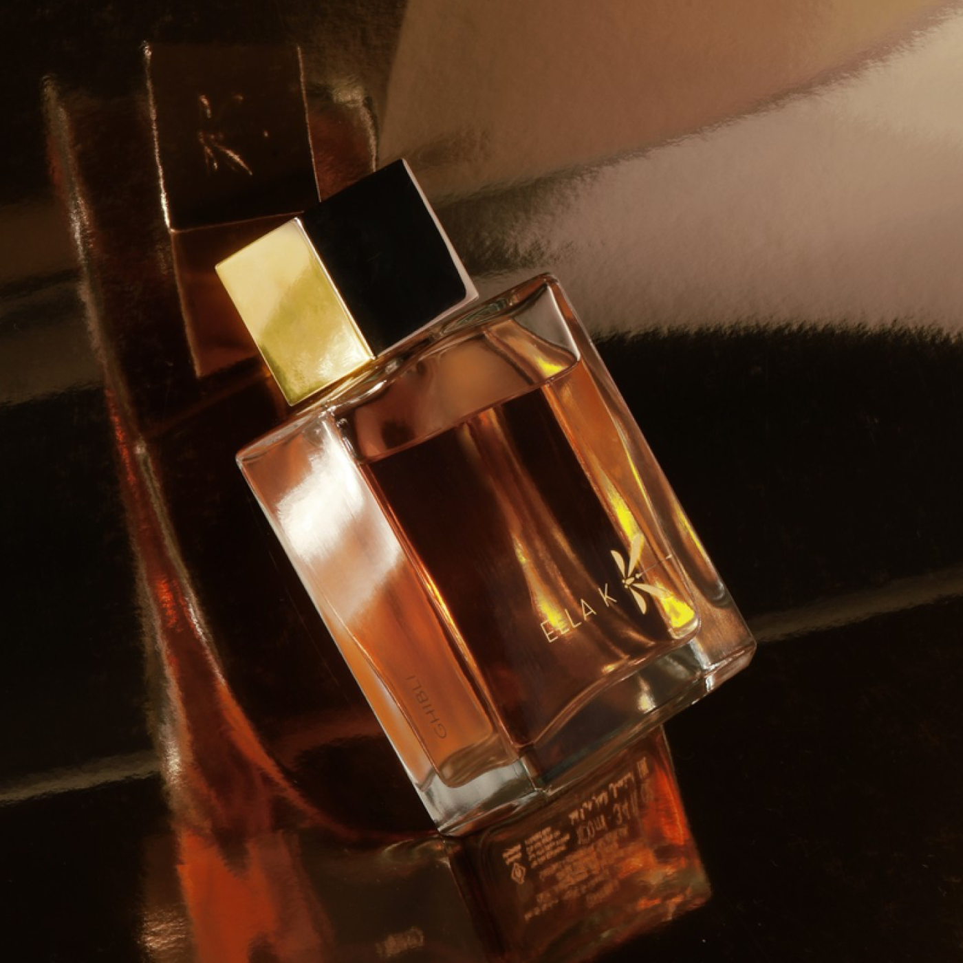 Flacon de parfum Ghibli au bouchon doré, éclairé par une lumière chaude sur une surface réfléchissante – élégant et mystérieux