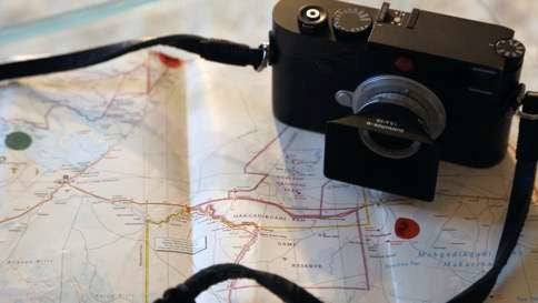 Appareil Leica sur une carte – symbole des voyages d’Ella K et de la quête olfactive à travers le monde.