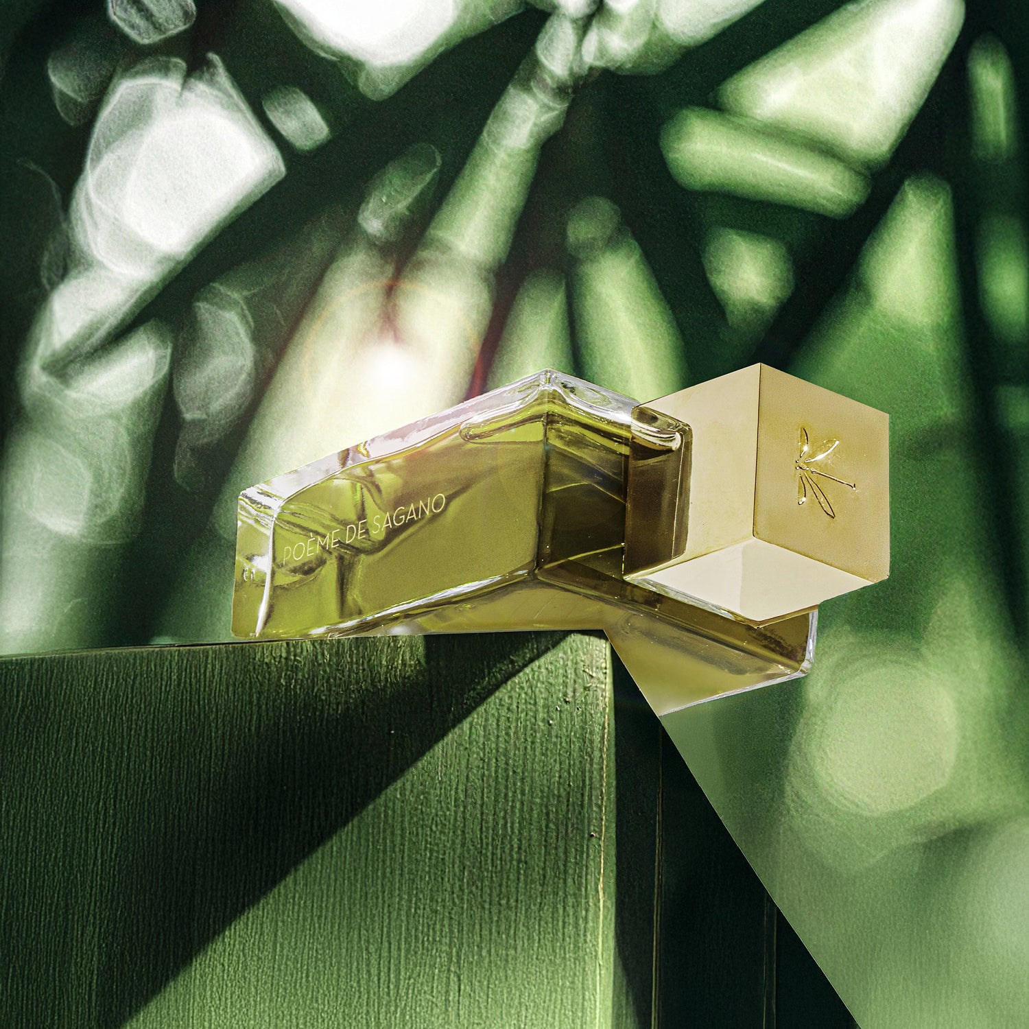 Le flacon de Poème de Sagano repose sur un bloc de bois peint en vert. La lumière du soleil traverse des feuilles de bambou et crée des reflets dorés sur le verre.