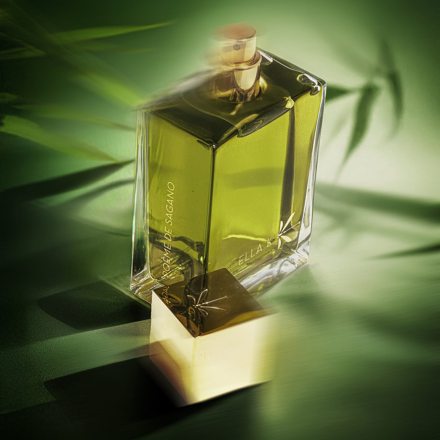 Le flacon ouvert de Poème de Sagano avec son pulvérisateur doré est posé sur un fond vert, baigné d’ombres douces de bambou.