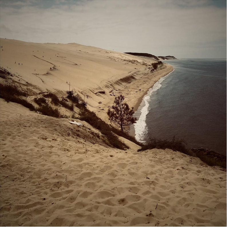Paysage majestueux de dunes s’étendant jusqu’à l’horizon, bordées par l’Atlantique – un lieu de silence et d’inspiration pour les parfums Ella K.