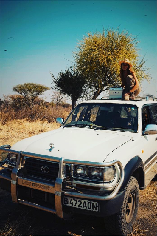 Sonia Constant sur un Land Cruiser blanc au cœur de la savane africaine – parfumeure en exploration, inspirée par l’immensité et le silence de la nature.