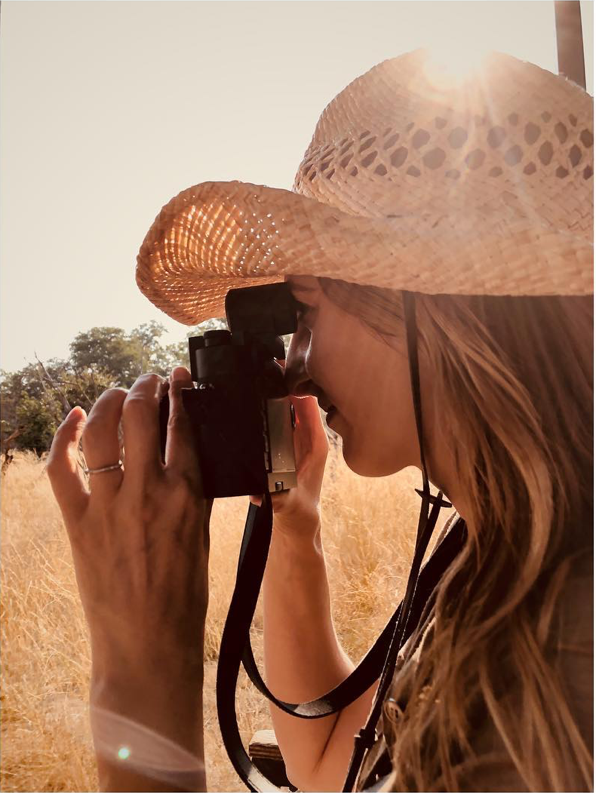 Sonia Constant, coiffée d’un chapeau de paille, appareil photo en main, baignée de lumière dorée – en quête des instants magiques qui inspirent ses parfums Ella K.
