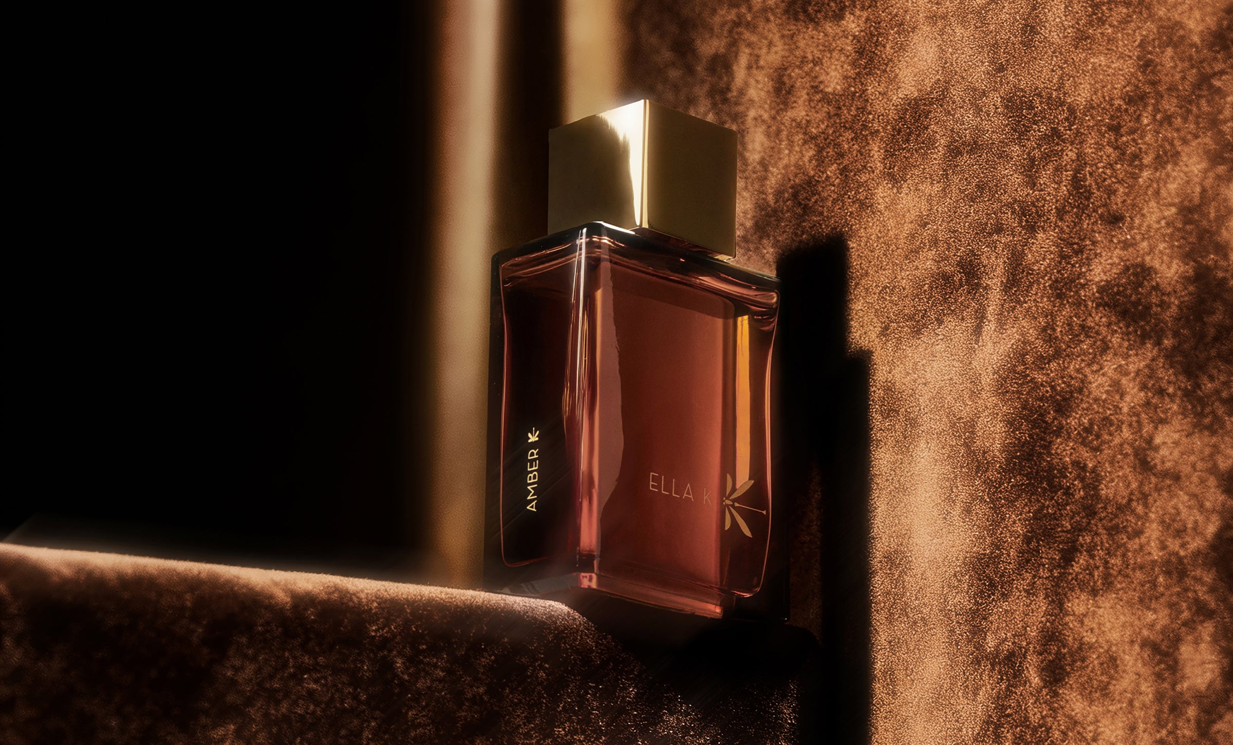 Flacon « Amber K » d’Ella K Parfums – baigné de lumière et d’ombres sur un velours doré, expression de profondeur, de caractère et de chaleur orientale.
