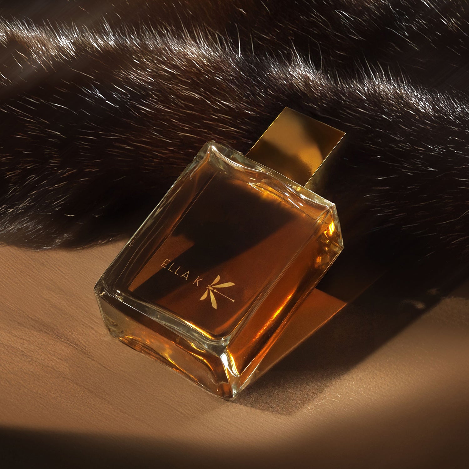 Flacon du parfum Mélodie de l’Altaï d'Ella K posé sur une surface sableuse, accompagné d’une fourrure sombre – une scène évoquant l’élégance sauvage et les vastes étendues.
