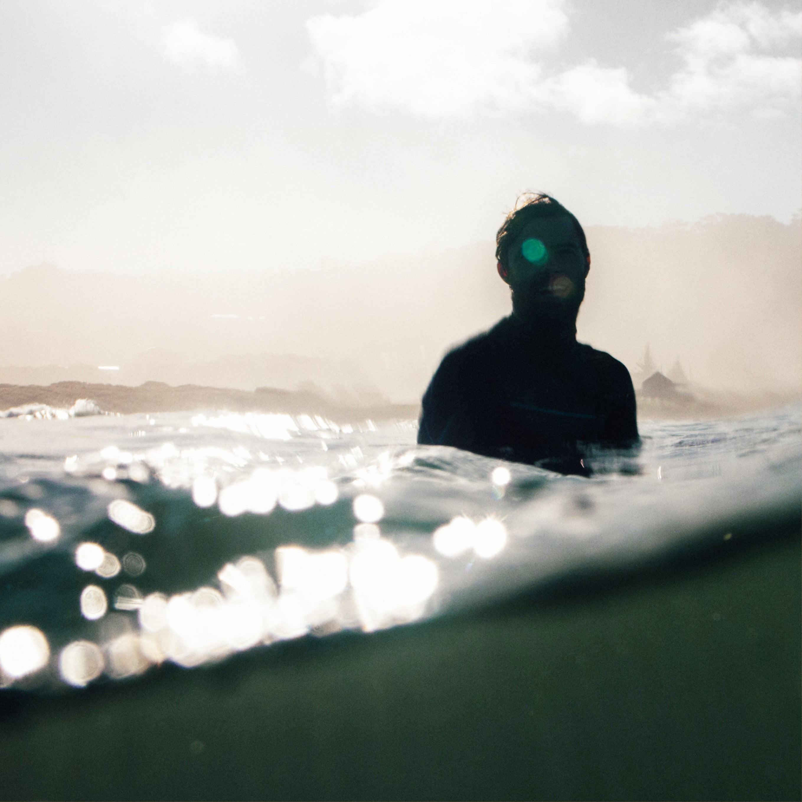 Silhouette sensuelle d’un homme dans l’eau, éclairé par une lumière dorée. Une immersion visuelle dans la sensualité mystérieuse de Musc K, le parfum mixte d’Ella K Parfums.