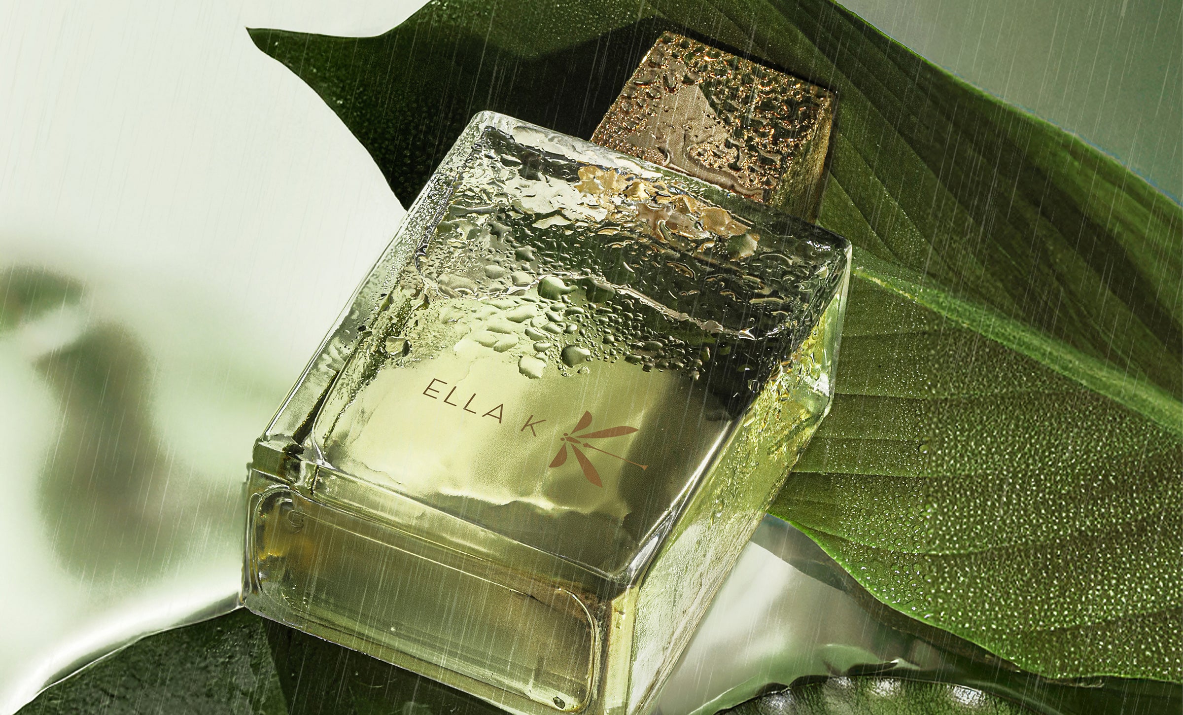 Flacon mouillé du parfum Pluie sur Ha Long d’Ella K posé sur une feuille verte – gros plan évoquant la fraîcheur naturelle de la fragrance.