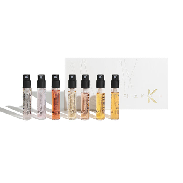 Coffret découverte Ella K avec sept mini-vaporisateurs en flacons de verre devant un étui blanc orné d’un marquage doré – sélection élégante d’échantillons parfumés
